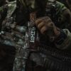 a man in camouflage holding a chocolate bar