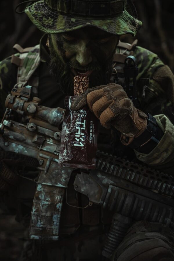 a man in camouflage holding a chocolate bar